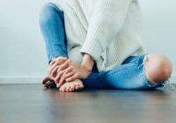 lower half of women sitting on floor with hands on feet - acupuncture menopause