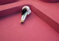 women sitting hunched over on red background - indicated for period problems