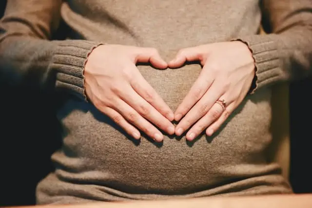 pregnant women holding hands in heart shape over - pregnancy acupuncture